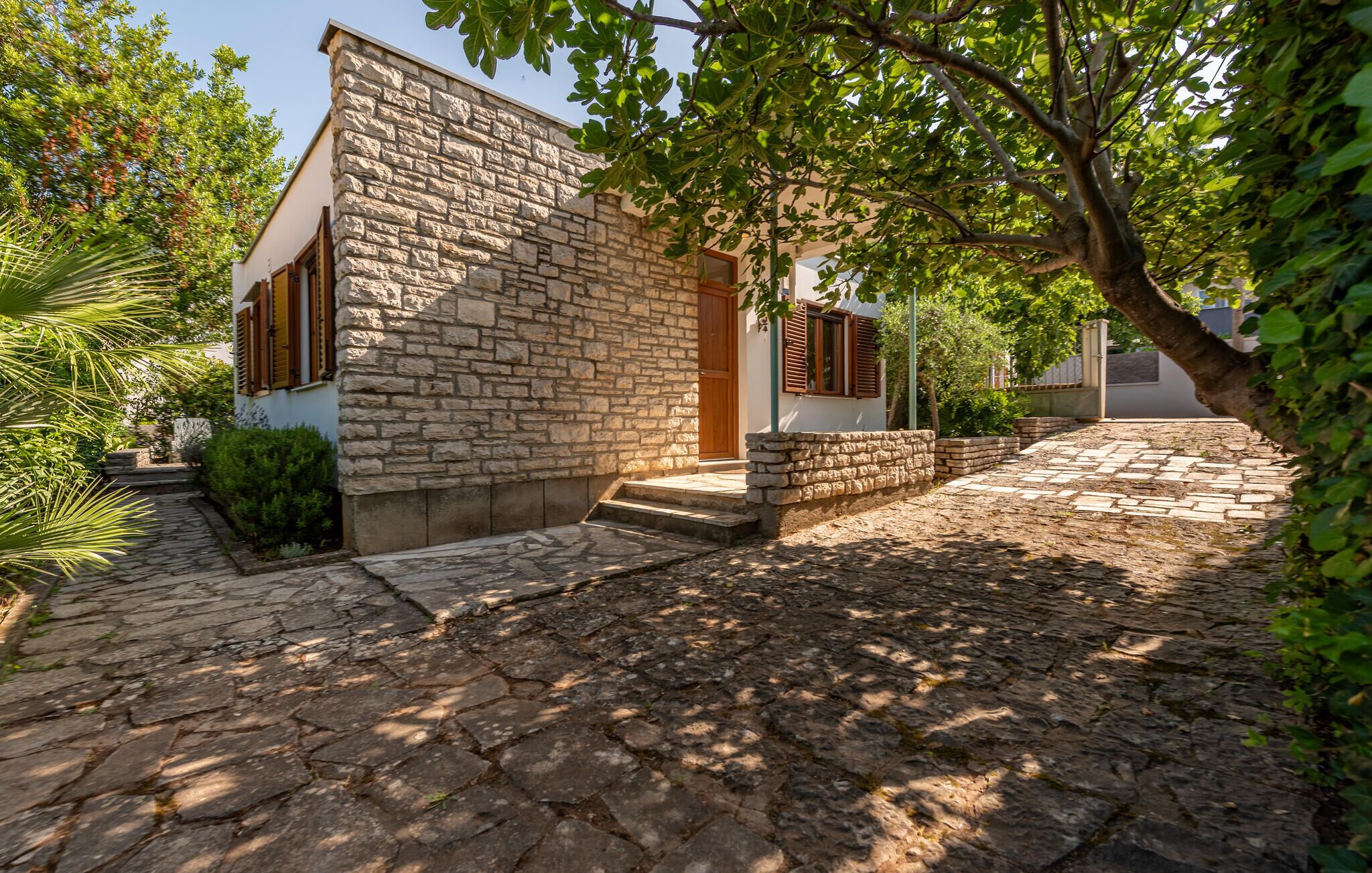 Un edificio de piedra con puerta de madera y escalones que conducen a un patio empedrado.