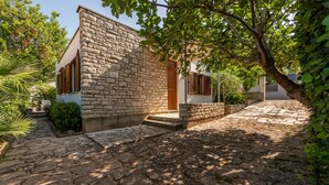 A stone building with a wooden door and steps leading to a paved courtyard.