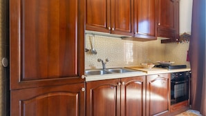 Una cocina con armarios de madera, un lavamanos de acero inoxidable y un horno empotrado.