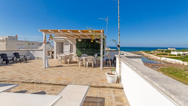 Terraza en la azotea con mobiliario exterior, una pérgola y vistas al mar.