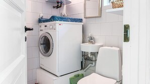 Een kleine badkamer met een voorlader wasmachine, een wastafel en een toilet.
