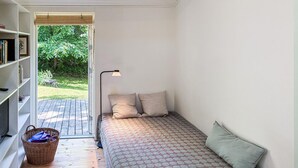 Een knus slaapkamer met een enkel bed, een nachtkastje, een lamp en een boekenplank.
