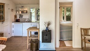Een compacte keuken met witte kastjes, een houten tafel en een klein fornuis.