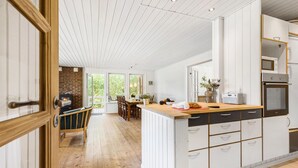 A spacious kitchen with white cabinetry, a wooden countertop, and a brick fireplace. - 4 bedroom nice home in Glesborg (Glesborg)