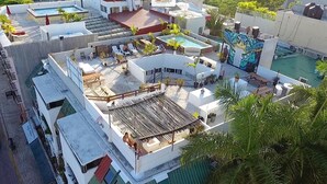 A rooftop terrace with multiple pools, outdoor seating, and a mural. - Izsla Hostel (Playa del Carmen)
