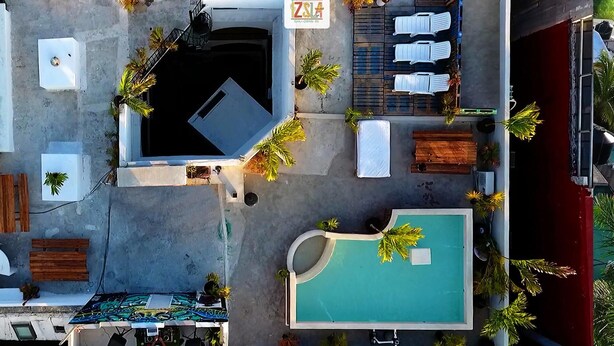 An aerial view of a hotel with a swimming pool, lounge chairs, and a small bar area. - Izsla Hostel (Playa del Carmen)