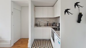 A compact kitchen with white cabinets, a marble backsplash, and a black and white checkered floor.
