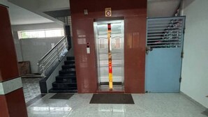Un hall d’entrée avec un escalier, une porte bleue dotée d’une grille métallique et un pilier rouge sur lequel est apposée une enseigne.