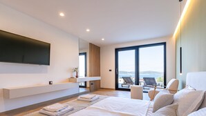 Un dormitorio moderno con una cama grande, un televisor montado en la pared y un balcón con vistas.
