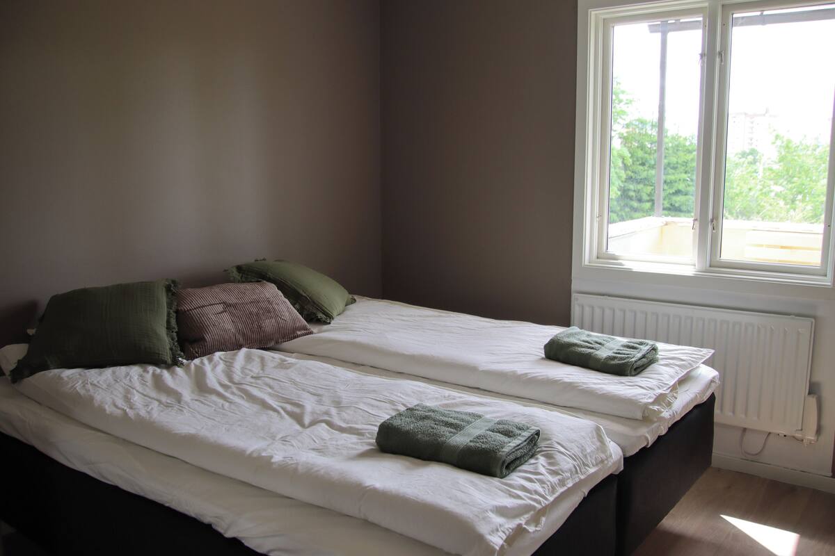 Ein Schlafzimmer mit zwei Betten, einem Fenster und einer Heizung.