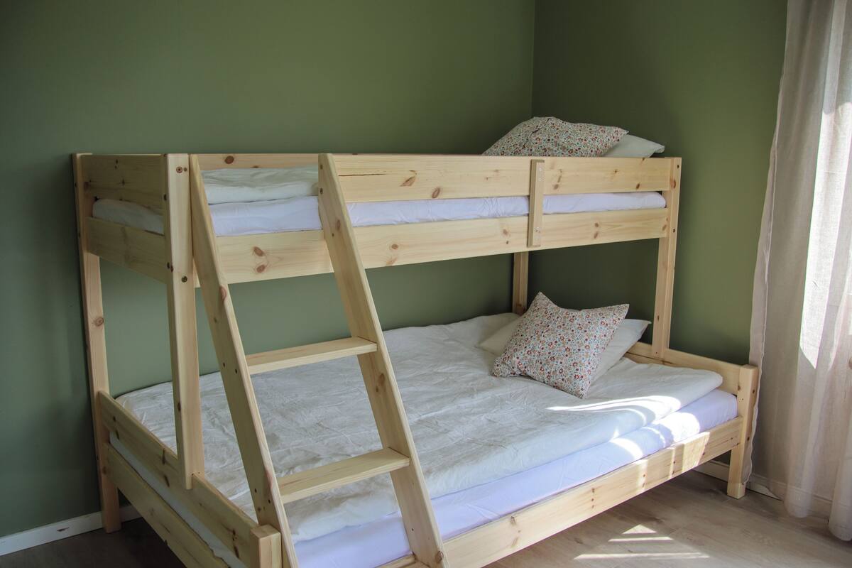 Ein Etagenbett mit zwei Schlafstellen, Holzrahmen und weißer Bettwäsche.