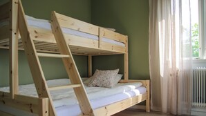 A bunk bed with a ladder, a window with curtains, and a radiator. - Pintro B&B (Hagfors)