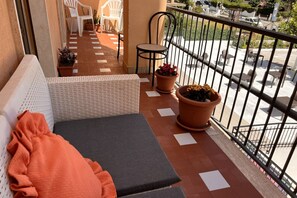 A balcony with a wicker sofa, a small round table, and potted plants.