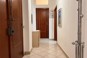 Un couloir avec une porte en bois, un petit comptoir et un tableau encadré accroché au mur.