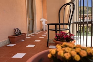 A balcony with a chair and potted plants.
