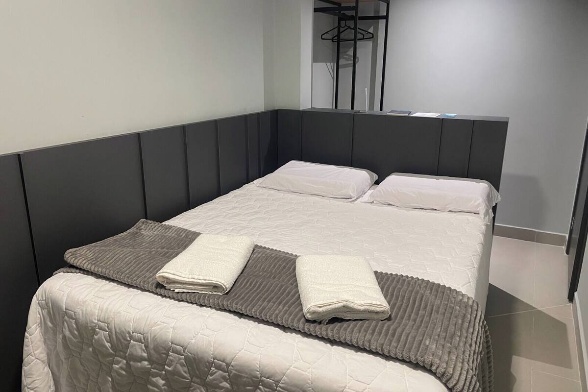 A single bed with a headboard, a bedside table, and a hanging coat rack.