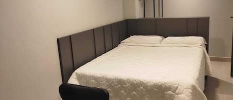 A bedroom with a bed, a chair, and a table.