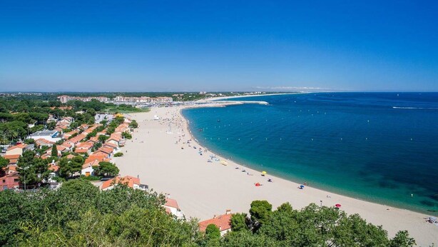A coastal town with a sandy beach, clear blue sea, and residential buildings with red roofs. - House with character, spacious rooms, wooded garden, quiet, free parking (Argelès-sur-Mer)