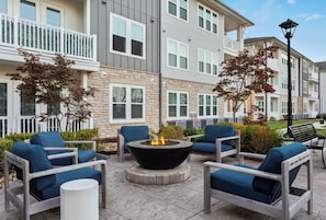 A courtyard with outdoor seating, a fire pit, and a stone building with multiple windows and balconies.