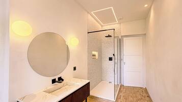Un bagno moderno con un ampio specchio, un vanità con piano in marmo, una doccia con porta in vetro e un pavimento piastrellato.