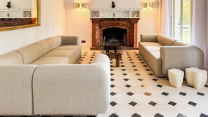 A living room with a brick fireplace, beige sofas, and a patterned floor.