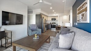A modern living room with a sofa, coffee table, and a TV. - Landing | Chic 2BD, Gym, Pool (Phoenix)