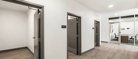 A modern hallway with sliding doors, a fire alarm, and a reception area with a desk and chairs.