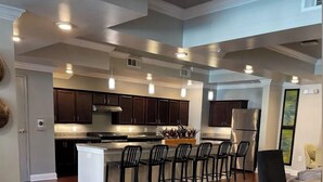 Una cocina amplia con armarios de madera oscura, una isla central con taburetes de bar y un refrigerador grande.