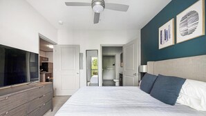 Une chambre à coucher avec un lit, un téléviseur, un ventilateur de plafond et des œuvres d’art accrochées au mur.
