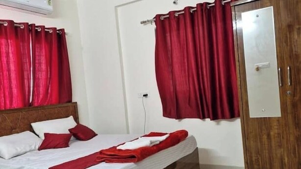 Une chambre à coucher avec un lit en bois, des rideaux rouges, une armoire et un mur blanc.