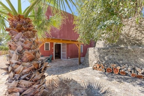 A building with a red exterior, a covered patio area, and a stack of firewood.