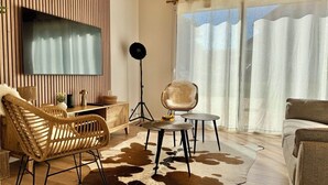 A modern living room with a large flat-screen TV, a round coffee table, a sofa, and a chair.