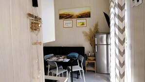 A compact kitchen with a dining area, a refrigerator, and a wall-mounted phone.