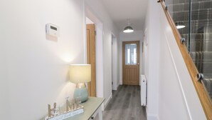 En gang med en trædør i enden, et lille bord med en lampe, og et skilt der står "sweet beach house".