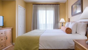 A hotel room with a bed, a television, a desk, and a lamp. - Beautiful 1 Bedroom Suite - Orlando, Florida! (Lake Buena Vista)