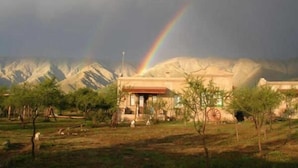Un bâtiment avec une chaîne de montagnes en arrière-plan et un arc-en-ciel.