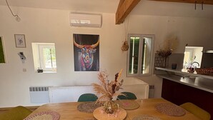 A dining area with a wooden table, green chairs, and a vase with dried plants.