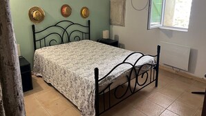 A bedroom with a bed, a nightstand, a lamp, a window, and a wall clock.
