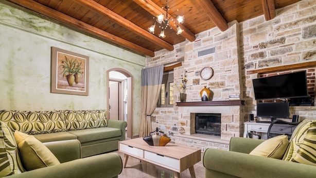 A cozy living room with a stone fireplace, a television, and a sofa.