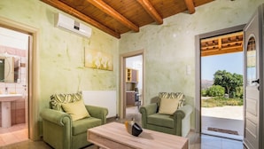 A living room with two green sofas, a wooden coffee table, and a painting on the wall.