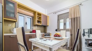 A compact kitchen with a dining table, chairs, and a coffee machine.