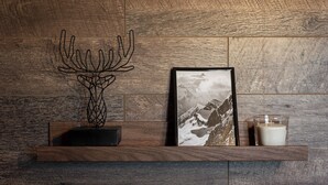 A wooden shelf with a framed picture of a mountain landscape and a candle.
