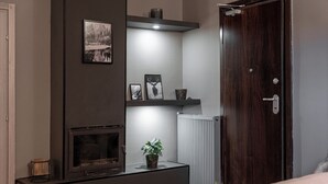 A modern living room with a fireplace, a dark wall, a white radiator, and a wooden door.