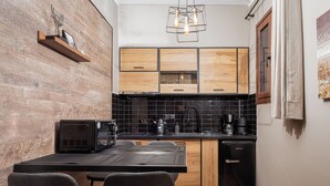 A compact kitchen with wooden cabinets, a black countertop, and a coffee machine.