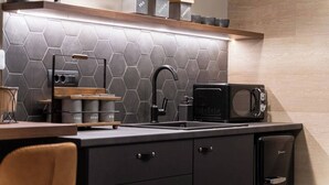 Una cocina moderna con un salpicadero de azulejos hexagonales, un grifo negro, una máquina de café y un microondas.