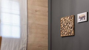 Una sala de estar moderna con un sofá gris, una mesita redonda con una planta, un tapete estampado, un radiador y dos obras de arte en la pared.