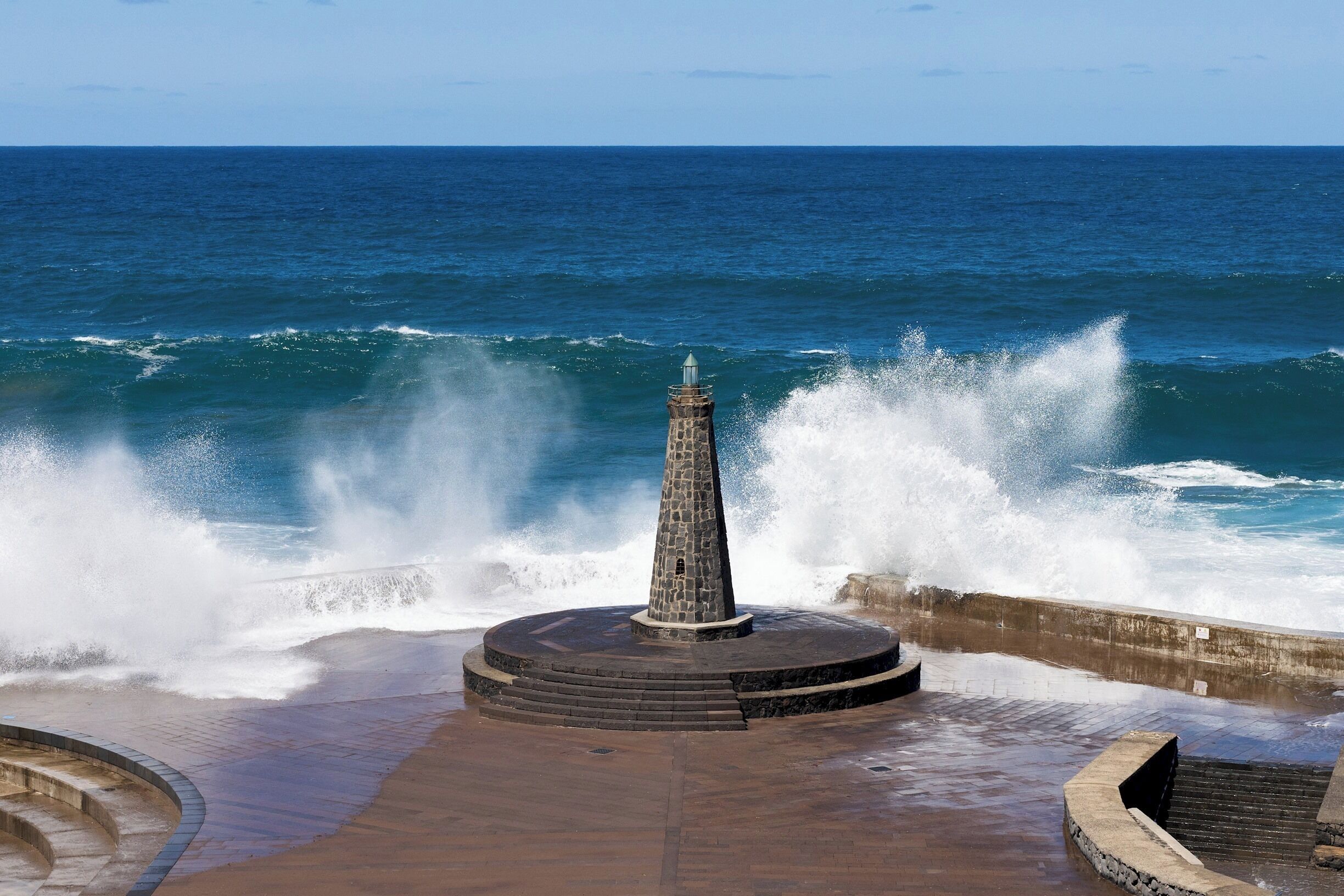 Un monumento de piedra junto al mar, con olas rompiendo cerca.