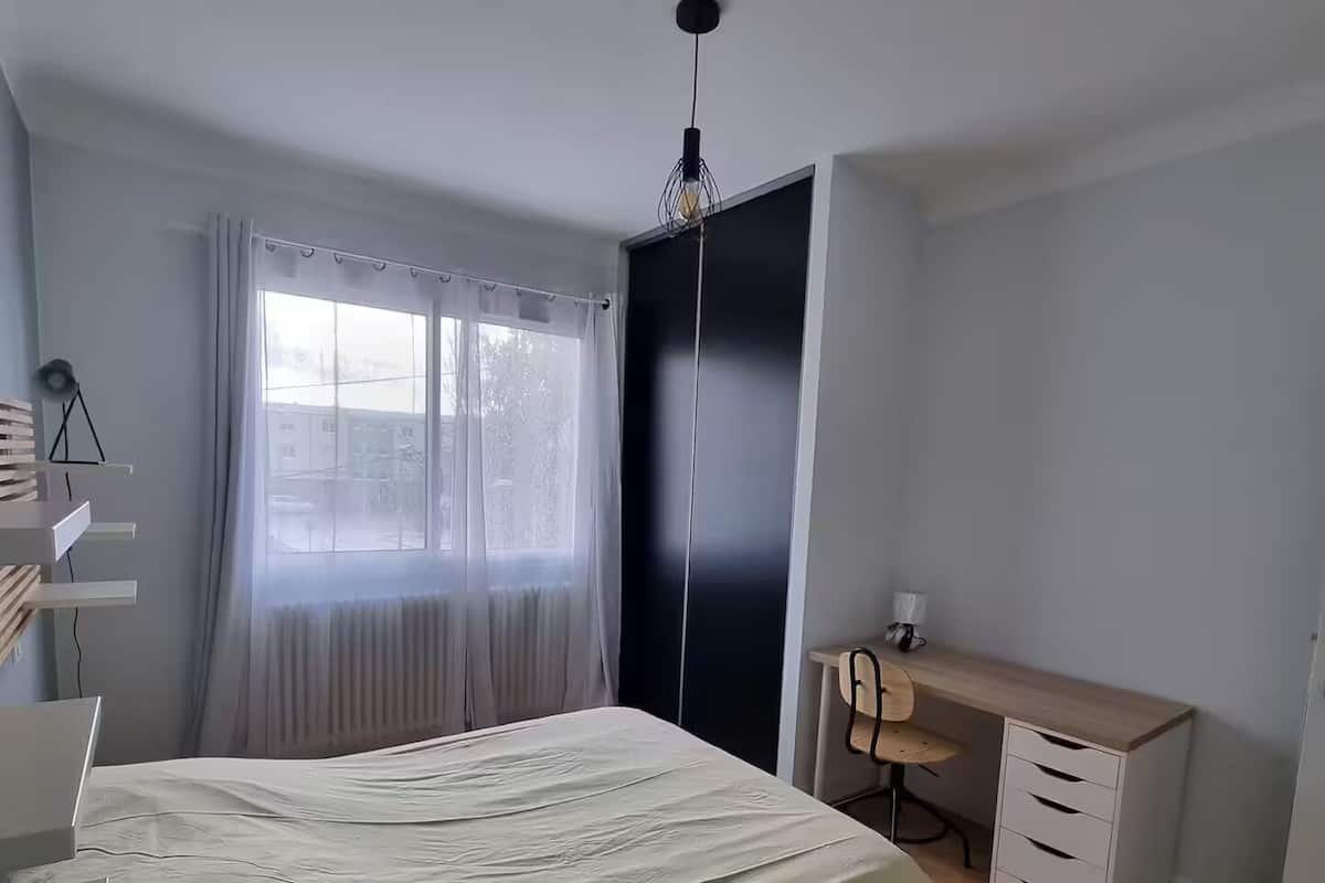 A bedroom with a bed, a desk, a chair, and a wardrobe.