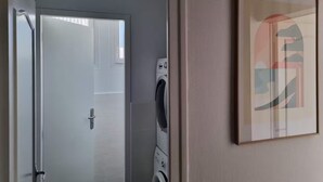 A room with a door leading to a laundry area, a washing machine, and a framed abstract artwork on the wall. - Les Cognassiers (Agen)