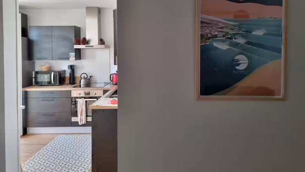 A modern kitchen with grey cabinets, a wooden countertop, and a red kettle. - Les Cognassiers (Agen)